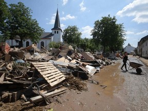 People remove debris in Iversheim, Germany, on Sunday, July 18, 2021.