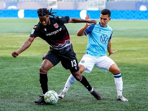 Ali Musse of Cavalry FC plays the ball away from Pierre Lamothe of HFX Wanderers FC during their Canadian Premier League match at IG Field in Winnipeg on Saturday, July 17, 2021.
