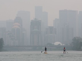 FILE - It was another smoke shrouded day in Calgary as two stand up paddleboarders cruised down the Bow River towards downtown on Monday, July 19, 2021.