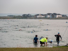 Athletes get out of Harmony Lake in Rocky View County after finishing the swimming part of the Ironman Triathlon on Sunday, Aug. 1, 2021.
