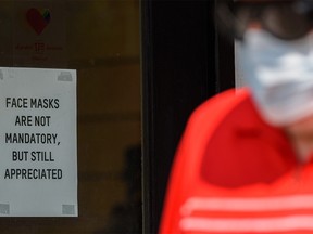 A masked pedestrian walks in front of a voluntary mask sign at a store on 17th Ave. S.W. on Tuesday, Aug. 3, 2021.