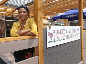Fay Bruney poses and shows one of the boards kicked out and damaged at Simply Irie restaurant on 6 St SW in Calgary on Wednesday, July 14, 2021. The popular restaurant has seen a rise in vandalism and theft since reopening after COVID-19.