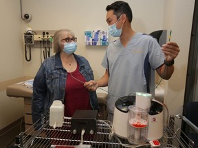 Brenda Crowell (L) speaks with interventional radiologist Dr. Jason Wong at Foothills Hospital in Calgary and is shown the Indigo Lightening CAT12 on Thursday, August 19, 2021. The new device was used on Crowell to quickly extract blood clots from her lungs in May. The device used for the first time in Canada saved Crowell's life after she developed a blood clot caused by COVID-19. Jim Wells/Postmedia