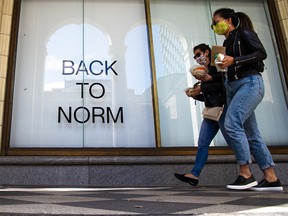 Pedestrians walk past a Hudson’s Bay store window sign in downtown Calgary on Tuesday, August 31, 2021.