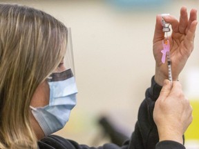 A public health nurse loads a syringe with the Pfizer COVID-19 vaccine.