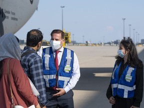 Immigration Minister Marco Mendicino (centre) and Maryam Monsef (right), Minister for Women and Gender Equality, welcome Afghan refugees who landed in Canada on Wednesday, Aug. 5, 2021.