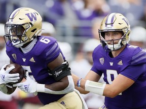 SEATTLE, WASHINGTON - SEPTEMBER 04: Dylan Morris #9 hands off the ball to Richard Newton #6 of the Washington Huskies during the first quarter against the Montana Grizzlies at Husky Stadium on September 04, 2021 in Seattle, Washington.