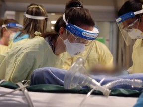 Teams in a crowded Calgary ICU work on a patient on a ventilator.