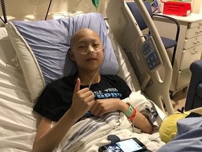 Julian Ho give a thumb's up from his bed at the Alberta Children's Hospital. Photo courtesy of Ho family.