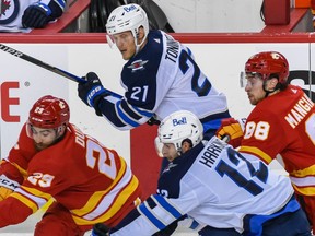 Calgary Flames Dillon Dube and Andrew Mangiapane battle for possession with a pair of Winnipeg Jets during the preseason finale at the Saddledome on Friday, Oct. 8.