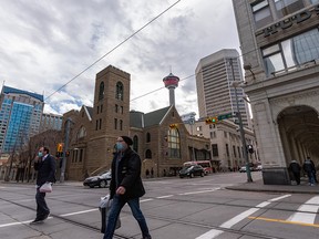 Masked pedestrians cross 7 Ave. S.W. in downtown Calgary on Monday, October 25, 2021.