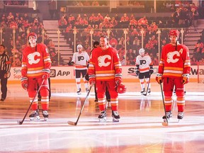 From left, the Calgary Flames’ Tyler Pitlick, Blake Coleman and Mikael Backlund stand for the national anthem prior to a game against the Philadelphia Flyers at the Scotiabank Saddledome in Calgary on Saturday, Oct. 30, 2021.