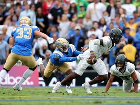 Oregon Ducks quarterback Anthony Brown escapes from Martell Irby (12) and Bo Calvert of the UCLA Bruins at the Rose Bowl in Pasadena, Calif., on Saturday, Oct. 23, 2021.