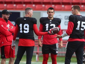 Stampeders quarterbacks (from left) Bo Levi Mitchell, Jake Maier and Michael O’Connor chat with a coach during practice at McMahon Stadium in Calgary on Thursday, Sept. 30, 2021.