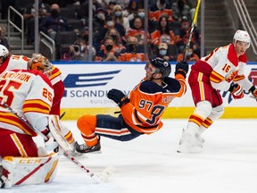 The Edmonton Oilers’ Connor McDavid collides with Calgary Flames goaltender Jacob Markstrom during preseason action at Rogers Place in Edmonton on Monday, Oct. 4, 2021.