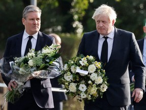 Britain's Prime Minister Boris Johnson (right) and Britain's main opposition Labour Party leader Keir Starmer carry floral tributes as they arrive at the scene of the fatal stabbing of Conservative British lawmaker David Amess, at Belfairs Methodist Church in Leigh-on-Sea, a district of Southend-on-Sea, in southeast England, Saturday, Oct. 16, 2021.