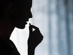 A young woman taking a pill.