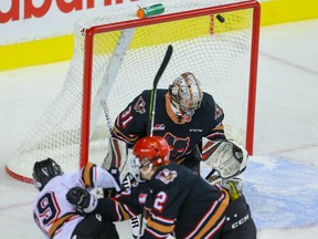 David Adaszynski of Team White scores on goalie Jack McNaughton of Team Black while being checked by Carter Yakemchuk during a Calgary Hitmen intrasquad game at the Saddledome in Calgary on Tuesday, Sept. 7, 2021.