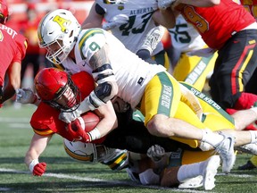 The University of Calgary Dinos’ Alessandro Molnar battles University of Alberta’s Orin Schellenberg at McMahon stadium in Calgary on Sunday, Oct. 24, 2021.