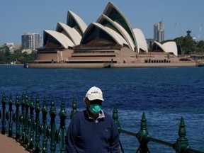 FILE PHOTO: A person in protective face mask walks along the harbour waterfront across from the Sydney Opera House during a lockdown to curb the spread of coronavirus disease (COVID-19) outbreak in Sydney, Australia, October 6, 2021. REUTERS/Loren Elliott/File Photo
