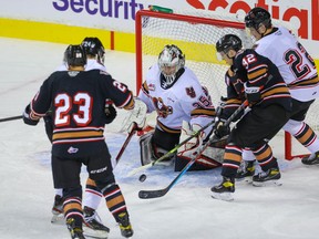 Goalie Brayden Peters of Team White makes a save on Oliver Tulk of Team Black as he battles Tyson Galloway in front of Zac Funk of Team White, and Adam Kydd of Team Black, during the Calgary Hitmen 2021 intersquad game at the Saddledome in Calgary on Tuesday, Sept. 7, 2021.