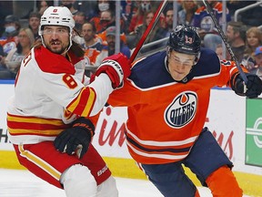 Calgary Flames defencemen Chris Tanev and Edmonton Oilers forward Jesse Puljujarvi battle for a loose puck during pre-season action at Rogers Place in Edmonton on Oct. 4, 2021.