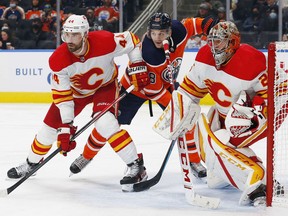 Calgary Flames defencemen Erik Gudbranson battles with Edmonton Oilers forward Zach Hyman in front of Flames goaltender Jacob Markstrom during a pre-season game at Rogers Place in Edmonton on Oct. 4, 2021.