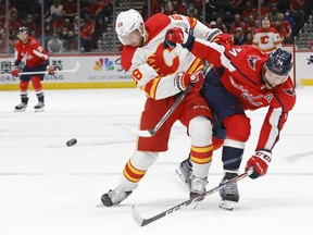 The Calgary Flames’ Elias Lindholm and Washington Capitals’ John Carlson battle for the puck at Capital One Arena in Washington on Saturday, Oct. 23, 2021.