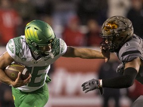 Travis Dye, of the Oregon Ducks, stiff-arms Nephi Sewell, of the Utah Utes, as he rushes the ball during Saturday's game at Rice-Eccles Stadium in Salt Lake City.