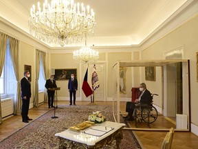 COVID-struck Czech President Milos Zeman, sits in a plastic cage as he appoints ODS leader Petr Fiala, left, as Czech Prime Minister at the Lany manor, near Prague, on Nov. 28, 2021.