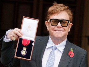 English singer Elton John poses with his medal after being made a member of the Order of the Companions of Honour for services to Music and to Charity, following an investiture ceremony at Windsor Castle in Windsor, England, Wednesday, Nov. 10, 2021.
