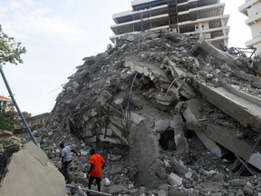 People walk to rescue workers from the rubble of a 21-storey building under construction that collapsed at Ikoyi district of Lagos, on Nov. 1, 2021.