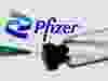 A syringe and vial are seen in front of a displayed Pfizer logo in this illustration PHOTO taken June 24, 2021.