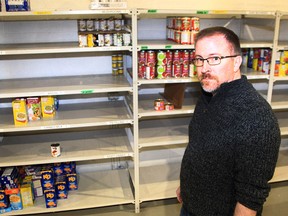 Charles Redeker, Operations Manager of the Veterans Association Food Bank, poses for a photo near partially empty shelves. The Veterans Association Food Bank has seen a significant decrease in donations over the past two years. Tuesday, November 9, 2021.