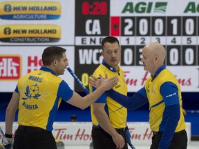 John Morris and skip Kevin Koe shake hands as Ben Hebert looks on following a game at the Brier earlier this year.