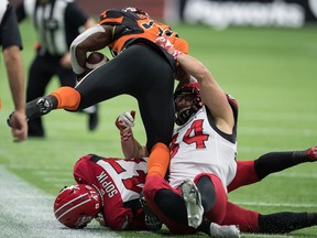 BC Lions' James Butler, (front left) is tackled by Calgary Stampeders' Ante Milanovic-Litre (34) and Fraser Sopik (47) during the first half of a CFL football game in Vancouver, on Friday, November 12, 2021.