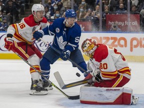Calgary Flames goaltender Dan Vladar (80) makes a save as defenceman Nikita Zadorov (16) tries to control Toronto Maple Leafs left wing Michael Bunting (58) during second period NHL action in Toronto on Friday November 12, 2021.