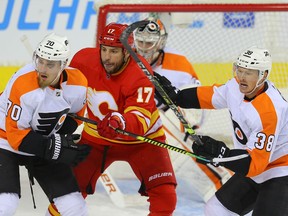 The Calgary Flames' Milan Lucic battles the Philadelphia Flyers' Rasmus Ristolainen and Patrick Brown at the Scotiabank Saddledome in Calgary on Saturday, Oct. 30, 2021.