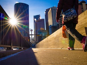 Pedestrians cross the Centre Street Bridge with downtown Calgary office towers as a backdrop on Wednesday, Nov. 24, 2021.