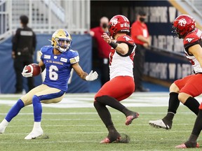 Winnipeg Blue Bombers kick returner Charles Nelson (left) puts on the brakes against the Calgary Stampeders at IG Field in Winnipeg on  Aug. 29, 2021.