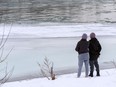 Two people share a moment by the half-frozen Bow River in East Village in Calgary on Tuesday, December 21, 2021.
