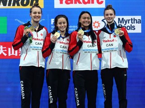 Summer MacIntosh, Kayla Sanchez, Katerine Savard and Rebecca Smith of Canada celebrate with their gold medals after winning the women’s 4x200-metre freestyle relay final during the FINA World Swimming Championships at Etihad Arena in Abu Dhabi on Monday, Dec. 20, 2021.