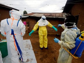 Kavota Mugisha Robert, a healthcare worker, who volunteered in the Ebola response, decontaminates his colleague after he entered the house of an 85-year-old woman, suspected of dying of Ebola, in the eastern Congolese town of Beni in the Democratic Republic of Congo, Oct. 8, 2019.