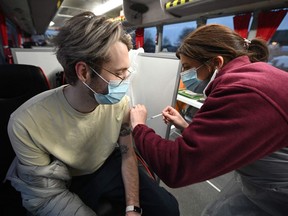 A member of the public receives his Covid-19 vaccine inside a National Health Service bus parked outside a supermarket in the town of Farnworth, near Manchester in north-west England on December 20, 2021, as the booster rollout accelerates in England.