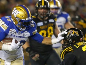 Winnipeg Blue Bombers running back Andrew Harris is taken down by the Hamilton Tiger-Cats' Simoni Lawrence at McMahon Stadium during the 107th Grey Cup in Calgary in this photo from Sunday, Nov. 24, 2019.