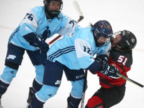 PWPHA'a Karell Emard (left) and Catherine Daoust hit Team Canada's Victoria Bach during women's hockey action at WinSport in Calgary on Saturday. Team Canada won 5-1.