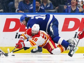 Pat Maroon of the Tampa Bay Lightning and Oliver Kylington of the Calgary Flames battle for the puck during the third period at Amalie Arena on Thursday night in Tampa.
