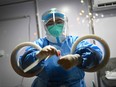 An employee, wearing a hazmat suit, holds a swab sample just collected during a daily COVID-19 PCR test on a member of the media ahead of the 2022 Winter Olympics in Beijing on Jan. 27, 2022.