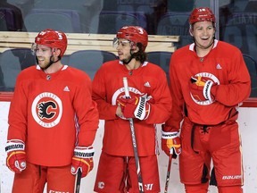 The Calgary Flames’ Elias Lindholm, Johnny Gaudreau and Matthew Tkachuk smile during a break in practice during training camp in Calgary on Jan. 4, 2021.