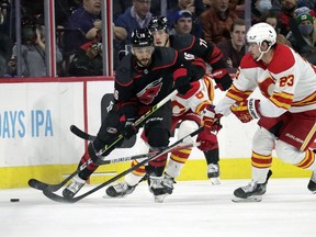 Carolina Hurricanes centre Vincent Trocheck, left, and right wing Jesper Fast, back center, battle Calgary Flames centre Sean Monahan for the puck at PNC Arena in Raleigh, N.C., on Friday, Jan. 7, 2022.